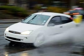 Voiture qui fait de l'aquaplaning sur une route mouillée sous la pluie